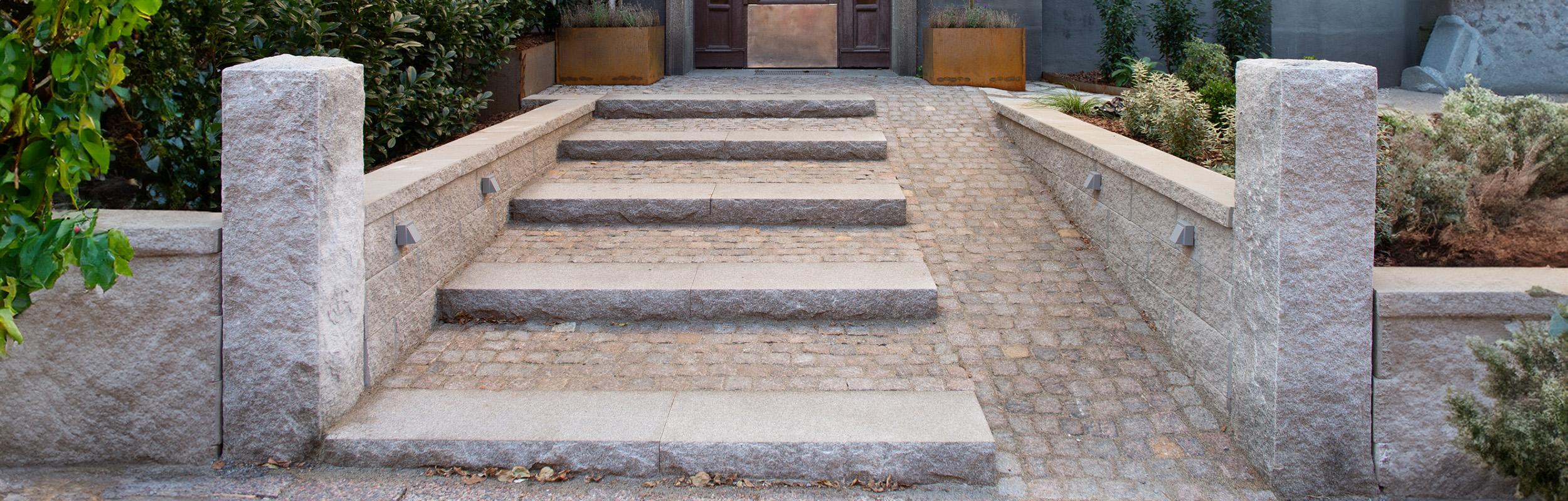 Gång med gatsten och trappblock samt stolpar i granit.