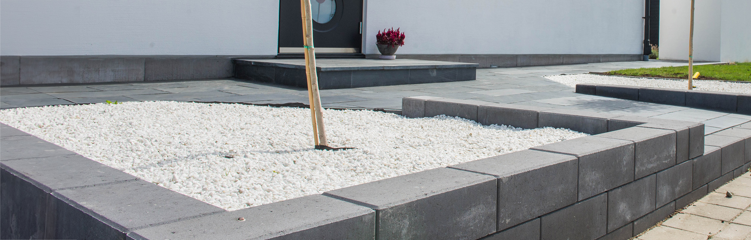 Marmorkross i stenrabatt inringat med en stödmur av murblock Basic